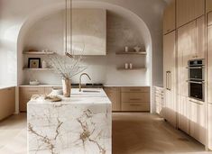 a large kitchen with marble counter tops and wooden cabinetry, along with an archway leading to the dining room