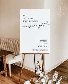 a white sign sitting on top of a wooden easel in front of a couch