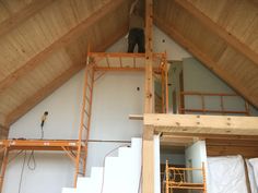 a man standing on top of a ladder in a loft next to another person climbing up the stairs