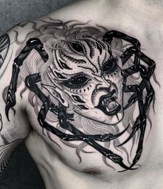 a man's chest with tattoos on it and an image of a demon in the middle