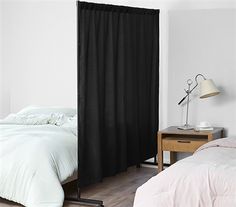 a white bed sitting next to a black curtain in a bedroom