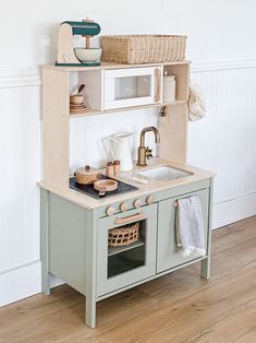 a toy kitchen with a sink, stove and microwave on it's shelf next to a wooden floor