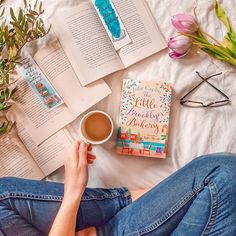 a person is laying on the bed with books and coffee