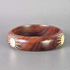 a wooden ring with sun and moon designs on it's sides, sitting on a gray surface