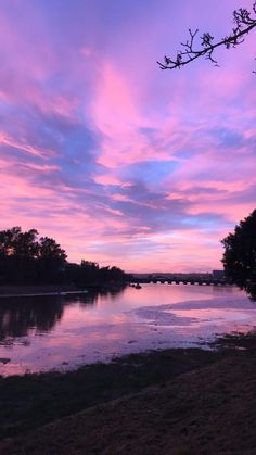 the sky is pink and purple as the sun sets on the horizon over a body of water