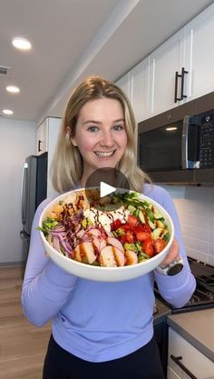 a woman is holding a large bowl of food