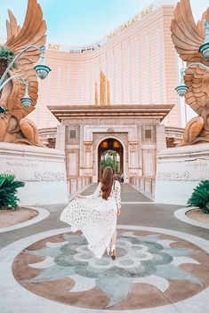 a woman in a white dress is walking through an entrance