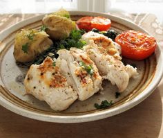 a white plate topped with meat and veggies on top of a wooden table