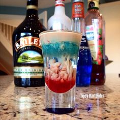 a shot glass filled with liquid sitting on top of a counter next to liquor bottles