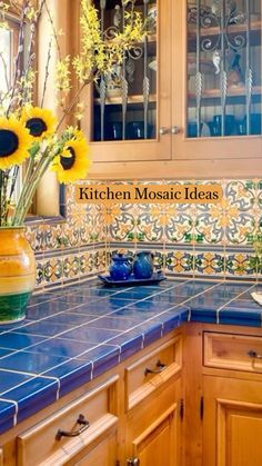 a kitchen with blue counter tops and sunflowers in a vase on the counter