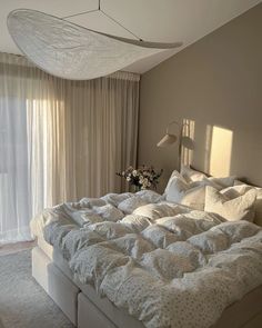 a large bed sitting in a bedroom next to a window with curtains on the windowsill