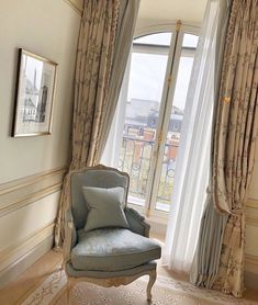 a chair sitting in front of a window next to a wall with curtains on it