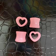 three pink heart shaped cups sitting on top of a black table next to each other