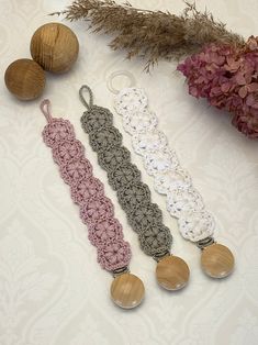 three crocheted laces and two wooden beads on a white table with flowers