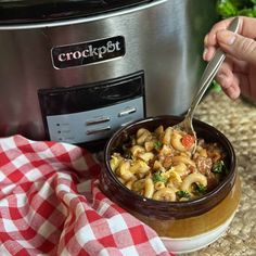 a person is spooning some food out of a crock pot