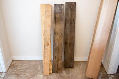 three pieces of wood sitting next to each other on the floor in front of a door