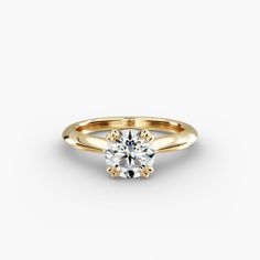 a yellow gold engagement ring with a round brilliant diamond in the center, on a white background