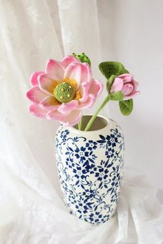 two pink flowers are in a blue and white vase on a white tableclothed surface