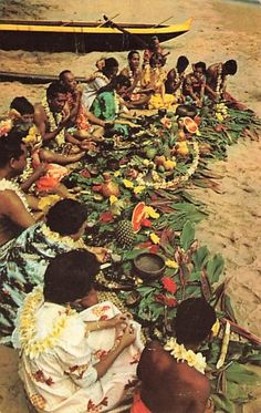 a group of people sitting on top of a sandy beach next to flowers and plants