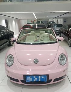 a pink vw beetle parked in a showroom