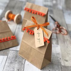 two small brown bags with orange string on them and a tag attached to the handles