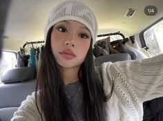 a girl with long hair wearing a white knitted hat and looking at the camera