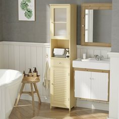 a white bath tub sitting next to a sink and a wooden cabinet in a bathroom