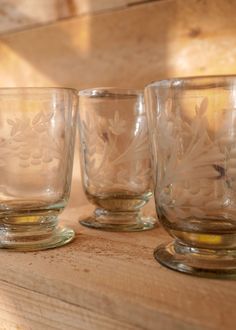 three glass cups sitting on top of a wooden table