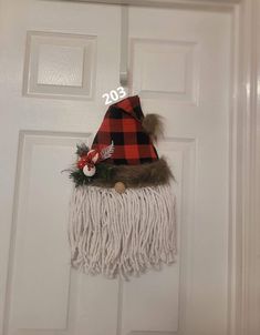 a door hanger with a red and black plaid hat on it's side