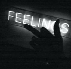 a person holding their hand up in front of a neon sign that reads, feelings