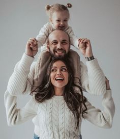 a man and woman holding a child on their shoulders