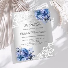 a wedding card with blue flowers and lace on the front, sitting next to a fan