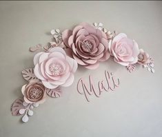 paper flowers are arranged in the shape of letters that spell out their name, on a gray background