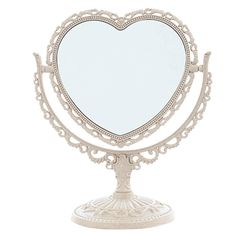 a white heart shaped mirror sitting on top of a metal stand with an ornate frame