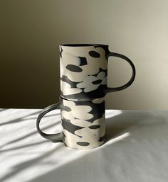 two black and white coffee mugs sitting on top of each other