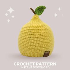 a crocheted yellow pear sitting on top of a white surface with stars in the background