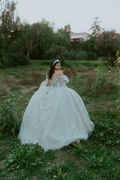 a woman in a white dress is walking through the grass