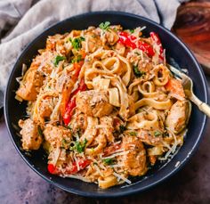 a black bowl filled with pasta and meat