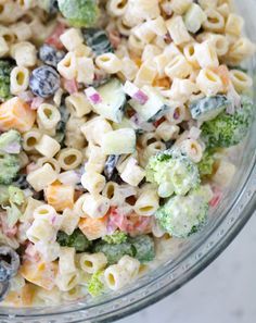 a glass bowl filled with pasta salad and broccoli