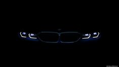 the front lights of a bmw car in the dark with its headlights turned on at night