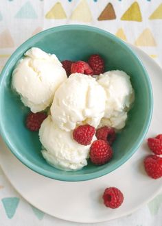 three scoops of ice cream with raspberries in a blue bowl on a white surface