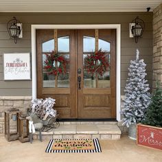 two christmas wreaths on the front door of a house with holiday decorations around it