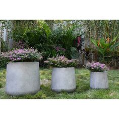 three cement planters sitting in the grass