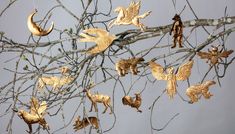 gold ornaments are hanging from the branches of a tree in front of a gray sky