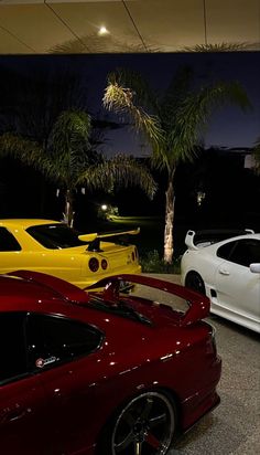 three different colored cars parked next to each other in front of a building at night