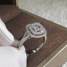 a diamond ring sitting on top of a white cloth covered cushion in a jewelry box