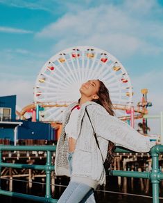 a woman standing in front of a ferris wheel with her eyes closed and looking up