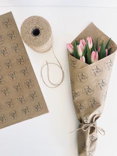 a bouquet of tulips wrapped in brown paper next to a roll of twine