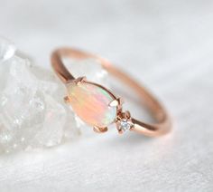 an opal and diamond ring sitting on top of some crystals