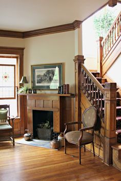 a living room filled with furniture and a fire place under a stair case on top of a hard wood floor